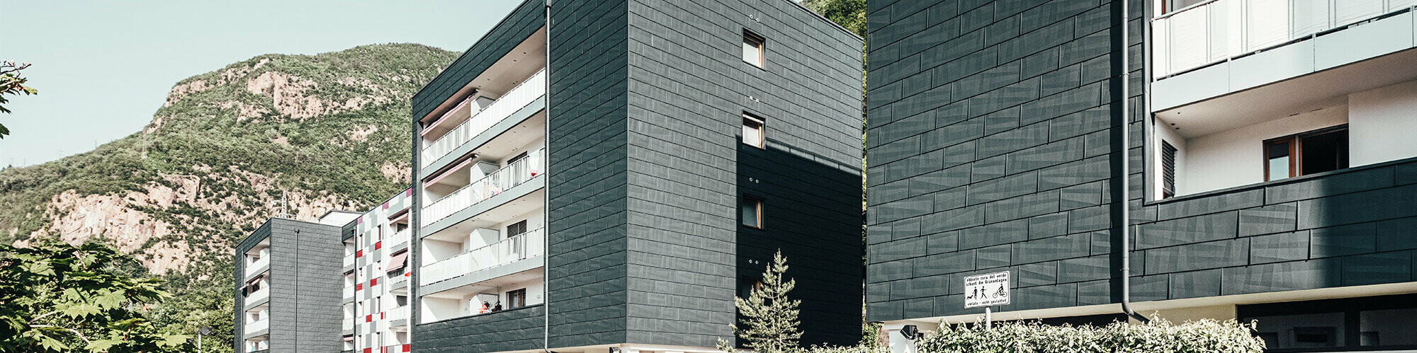 Vue de l'avancée du bâtiment rénové à Bozen. Les balcons avec leur balustrades blanches et la façade en panneaux de façade FX.12 Prefa.