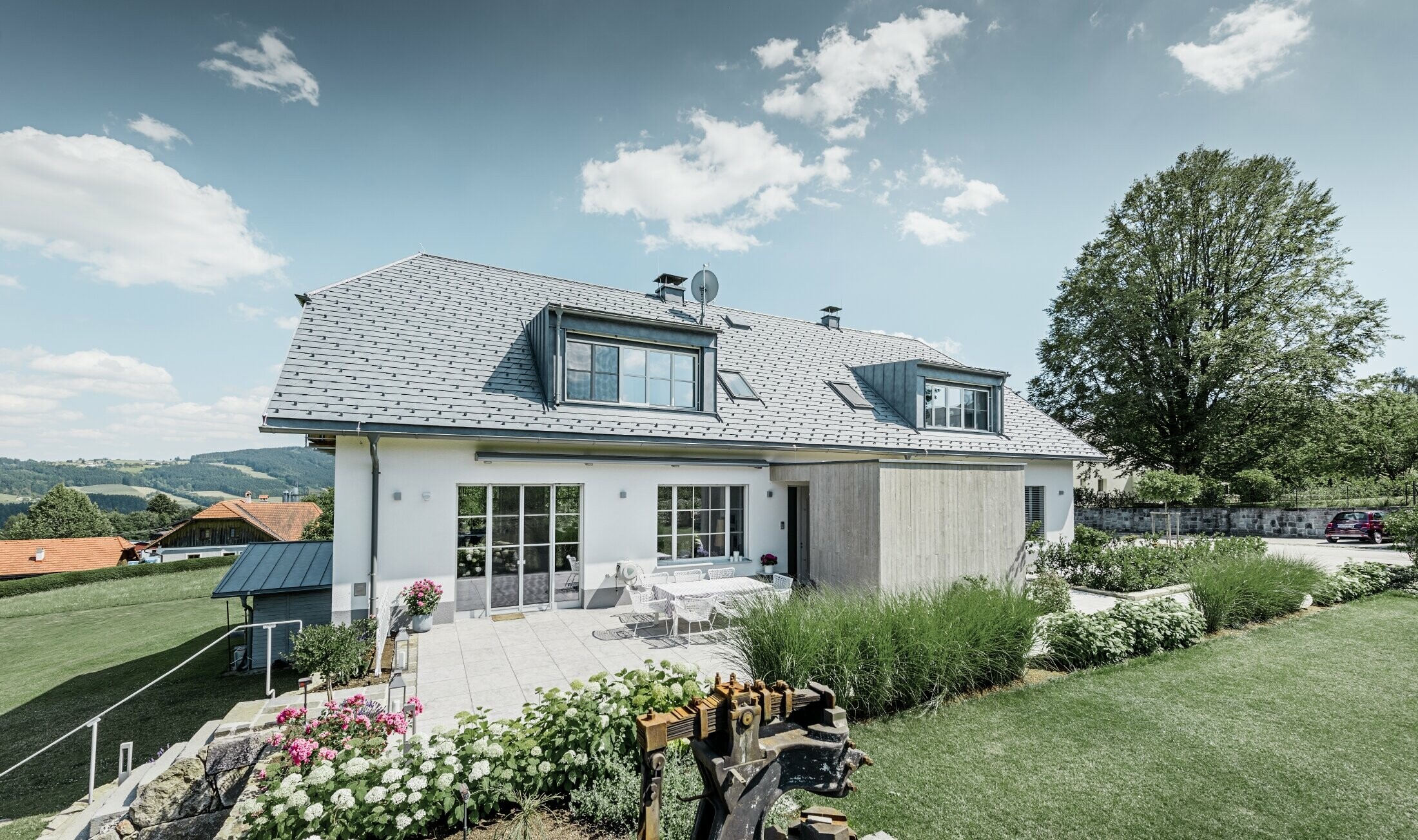 Classica casa unifamiliare con tetto a mezza anca. La casa è stata ristrutturata con scandole PREFA in grigio pietra, con un bel giardino e un’ampia terrazza.