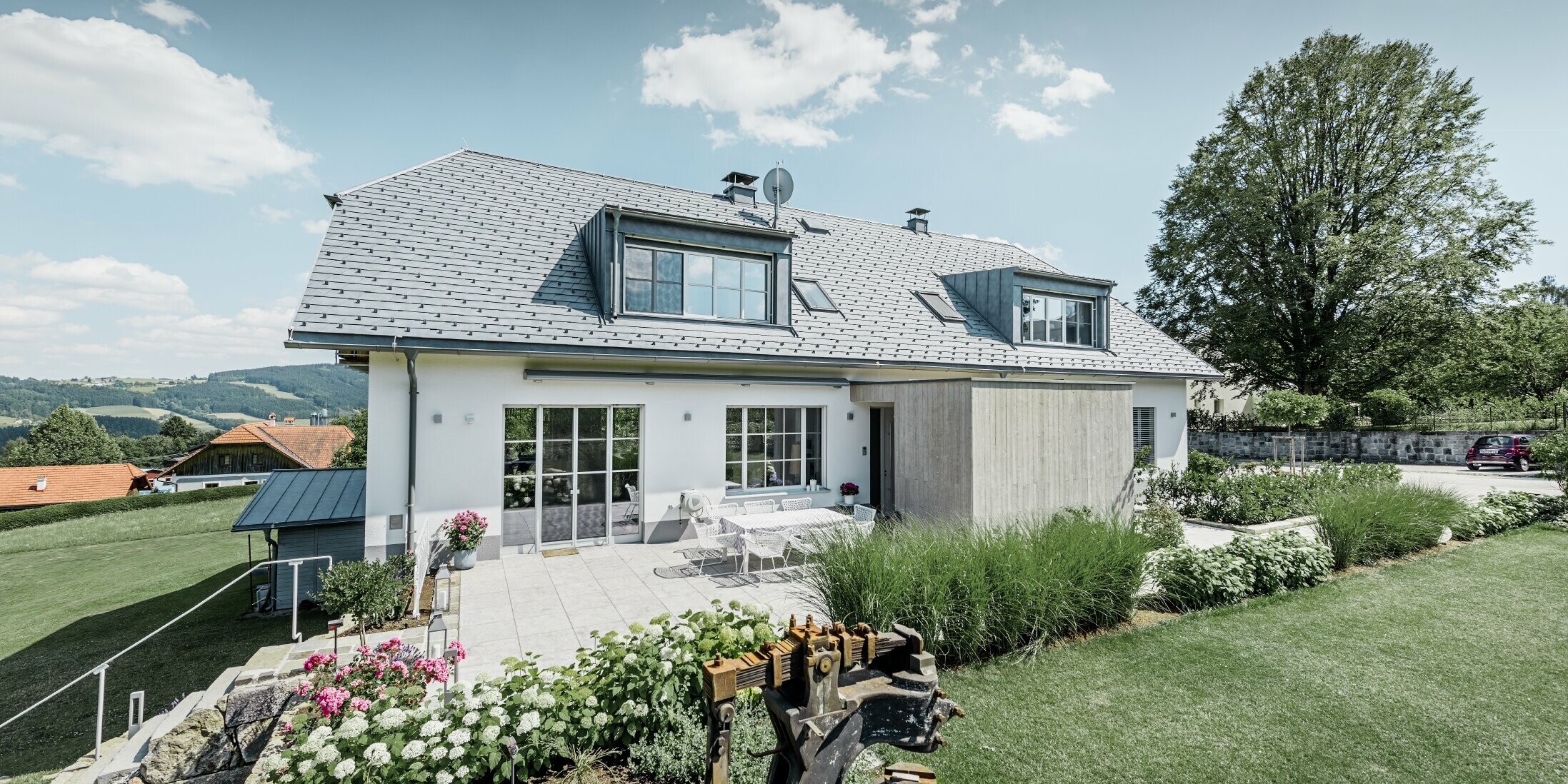 Klassisches Einfamilienhaus mit Krüppelwalmdach; Das Haus mit Dachsanierung mit der PREFA Dachschindel in Steingrau mit schön angelegtem Garten und großzügiger Terrasse.