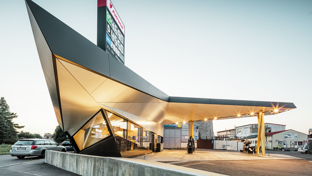 Seitlicher Blick auf die dynamische, mit Aluminium bekleidete Tankstelle von Architekt Daniel Zerzán: Etliche Dreiecke und Trapeze strukturieren die Fassade.