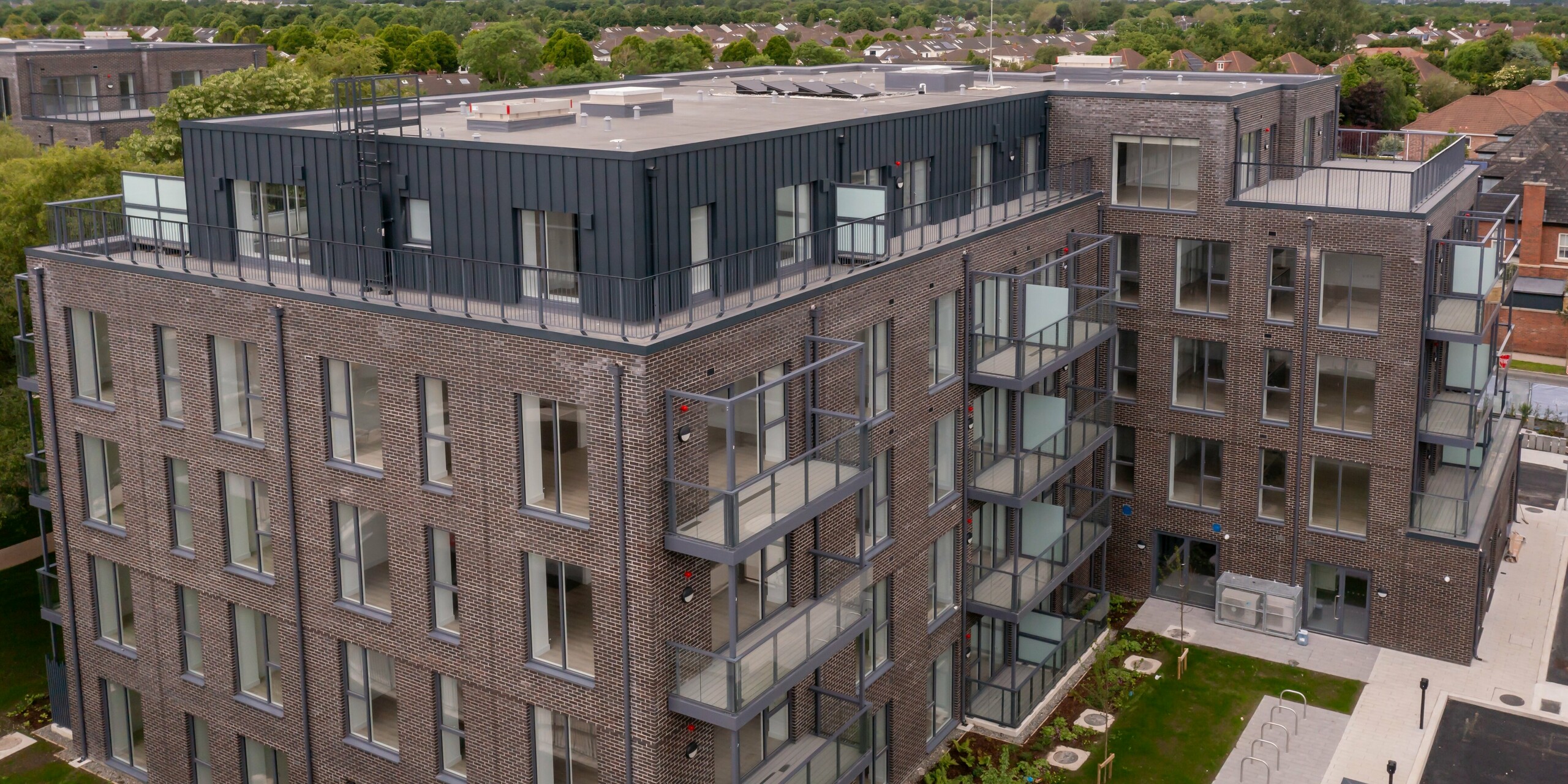 Frontansicht des Wohnkomplexes Balroy Hall in Dublin aus der Vogelperspektive. Die PREFALZ Aluminiumverkleidung in Anthrazit (P.10) bedeckt 800 m² der Fassade. Hochwertige Kombination aus modernem Design, langlebigem Aluminium und traditioneller Backsteinarchitektur.