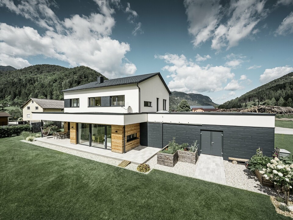 Maison individuelle moderne dans un environnement rural, avec les produits de toiture et de façade PREFA. 