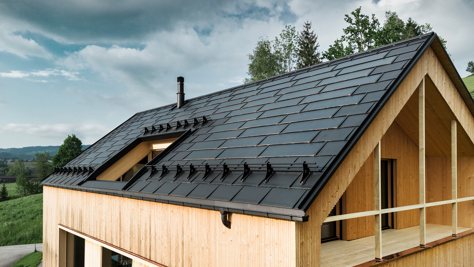 Tuile solaire PREFA noir sur une maison écologique à Egg, en Autriche - durable, économe en énergie et esthétique pour une architecture moderne. La tuile solaire innovante combine un toit résistant aux intempéries avec un système photovoltaïque. Les modules photovoltaïques intégrés s'intègrent harmonieusement dans le toit de la maison individuelle.