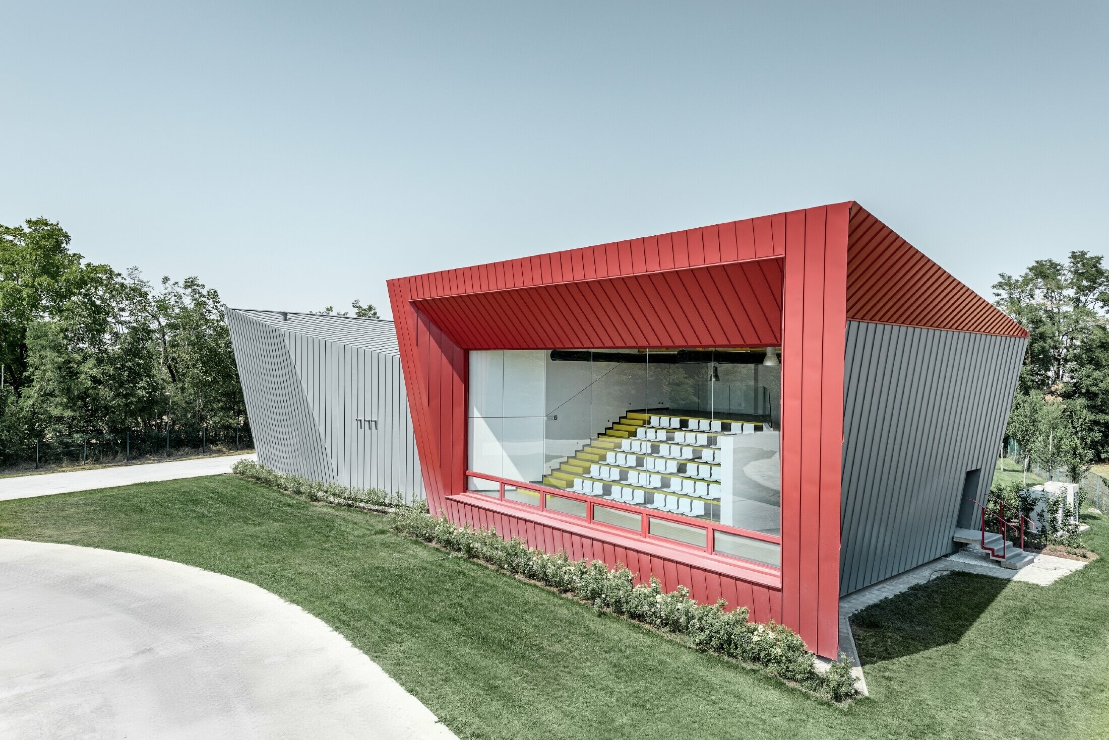 Centre d’entraînement moderne Dieci à Montecchio Emilia (Italie) — Façade des tribunes en aluminium réalisée avec des bandes Prefalz gris souris et Falzonal rouge carmin