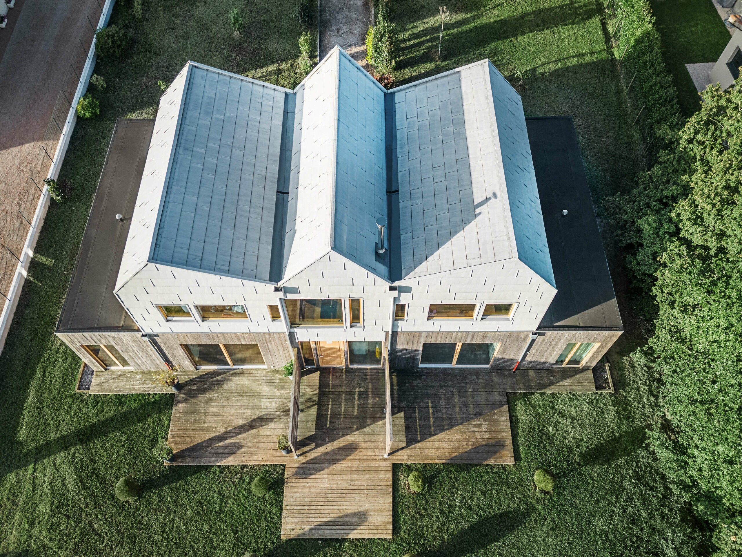 Vogelperspektive eines Doppelhauses mit Aluminium-Satteldach von PREFA. Das Dach zeichnet sich durch saubere Linien und eine moderne Oberfläche aus. Die Terrasse aus Holz ergänzt den modernen Charakter des Hauses.