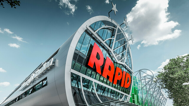 Ansicht des Allianz Stadions von SK Rapid Wien mit auffälliger PREFA Fassade in Form der Aluminium Verbundplatte in Silbermetallic. Die Gebäudehülle strahlt Dynamik und Moderne aus. Der Eingangsbereich, gekrönt mit dem leuchtend roten RAPID-Schriftzug, lädt ein in das Herz des Fußballs, eingefasst von einer futuristischen und zugleich eleganten Fassadenstruktur, die Sportarchitektur auf ein neues Niveau hebt.