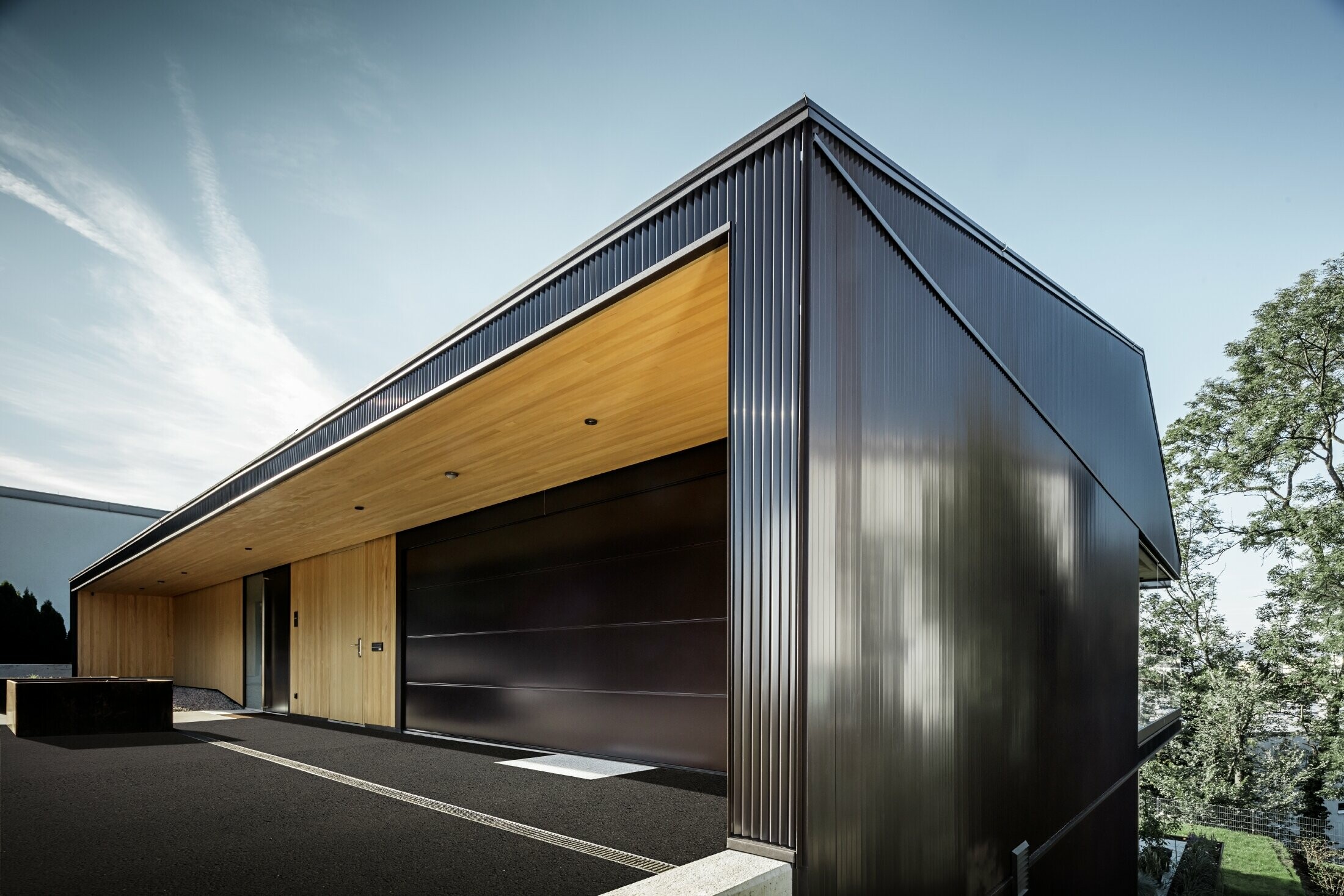 Accesso per garage di una casa unifamiliare, la facciata è rivestita con il profilo a zeta PREFA in marrone scuro. 