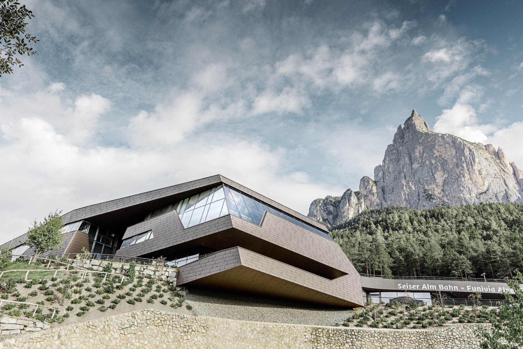 neu gestaltete Talstation der Umlaufbahn Seiser Alm, ähnlich der Dolomiten im Hintergrund mit unregelmäßigen Kanten und Oberflächen mit einer Aluminium Fassade in braun von PREFA