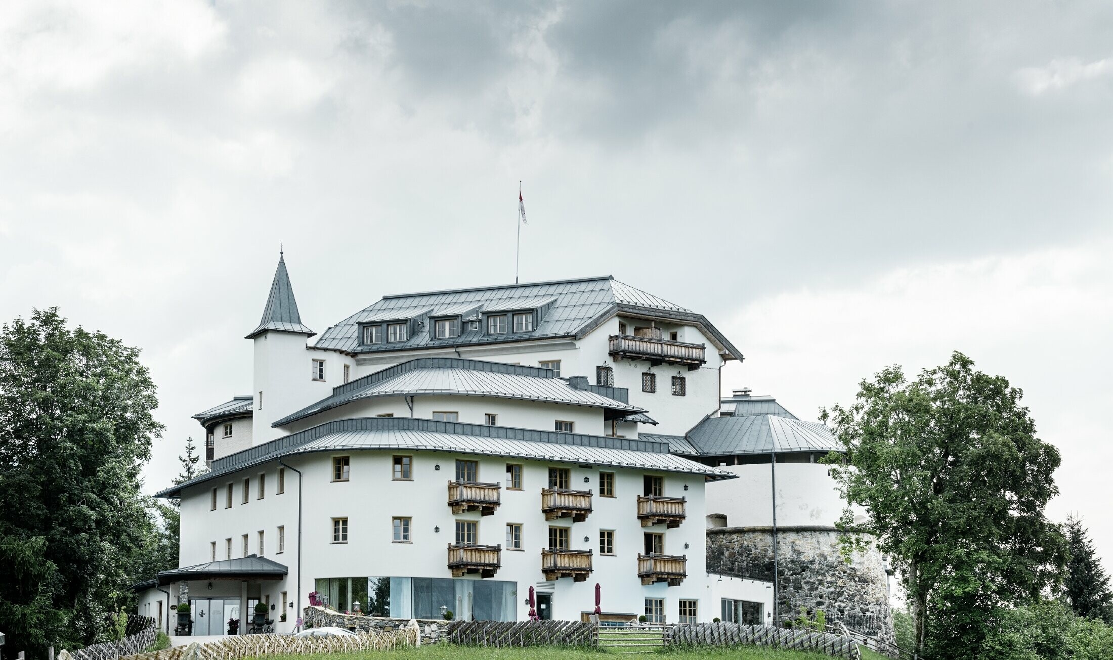 Castello Mittersill circondado da alberi e montagne con una copertura in Prefalz in grigio pietra ristrutturato