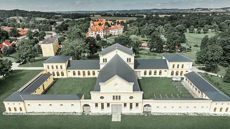 Veduta aerea della Marstall di Basedow, Germania; l’immagine offre un buono sguardo d’insieme dell’edificio con la nuova copertura in scandole PREFA in alluminio color antracite.