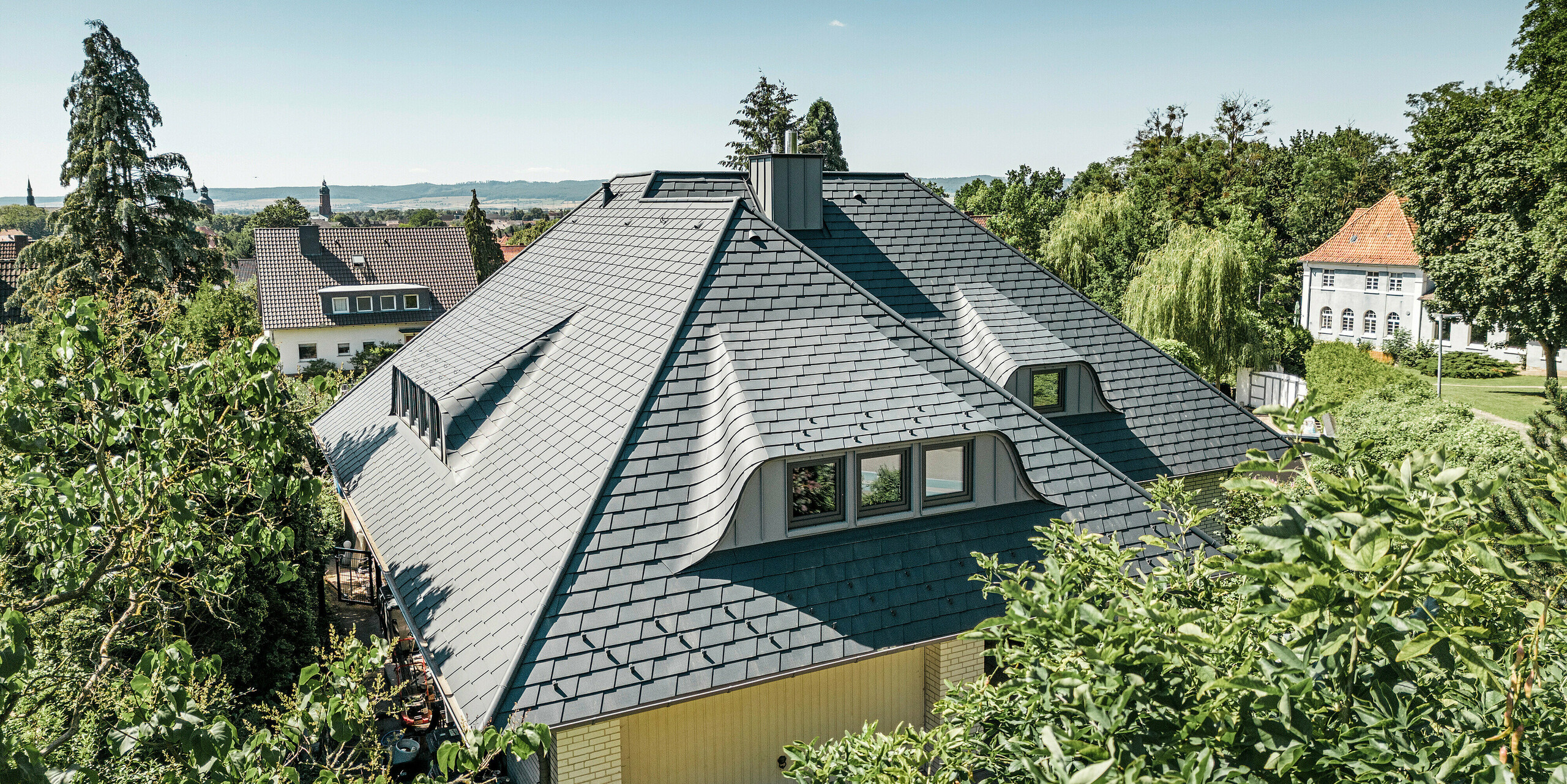 Toiture avec lucarnes cintrées d'une maison individuelle à Einbeck recouverte de bardeaux PREFA en anthracite P.10