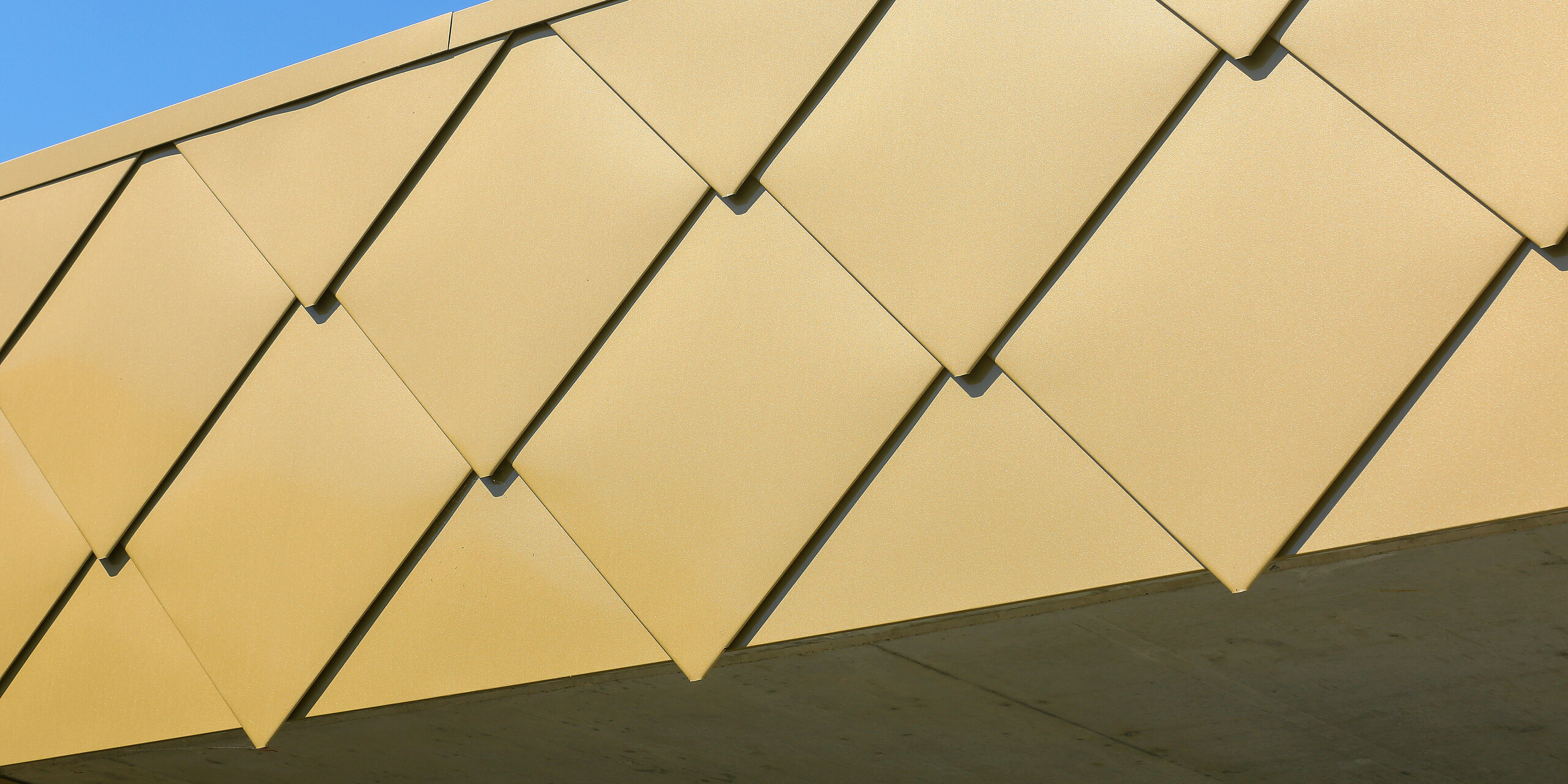 Plan détaillé des losanges de façade brillants PREFA 44 × 44 en Sparkling Gold au Centre Culturel de Fessenheim en France. Les remarquables losanges en aluminium font briller le bâtiment d'un or accrocheur.