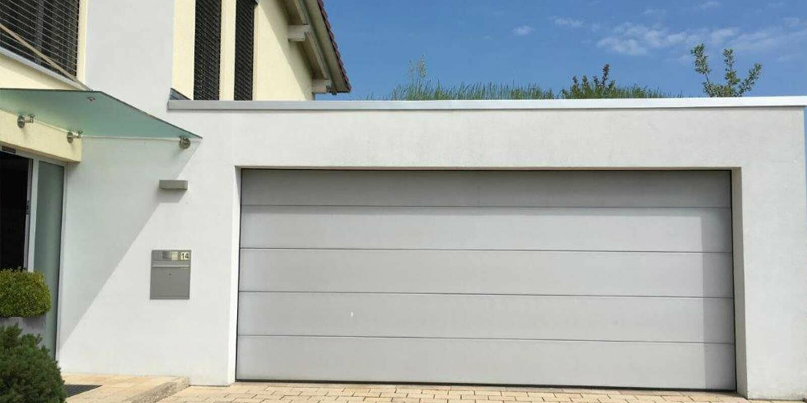 Garage prima della ristrutturazione con doghe di rivestimento PREFA color antracite, facciata bianca e portone bianco