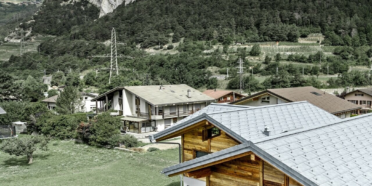 Immagine dall’alto dello Chalet Fabrice; il rifugio è stato rivestito con la tegola R.16 PREFA in grigio pietra con nasi paraneve, la parte superiore dell'edificio è rivestita da una facciata in legno rustica.