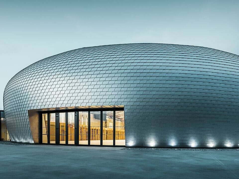 Die Sporthalle in Tschechien erinnert in ihrer Form an ein UFO - dazu wurden 20.000 PREFA Wandschindeln in Naturblank verlegt