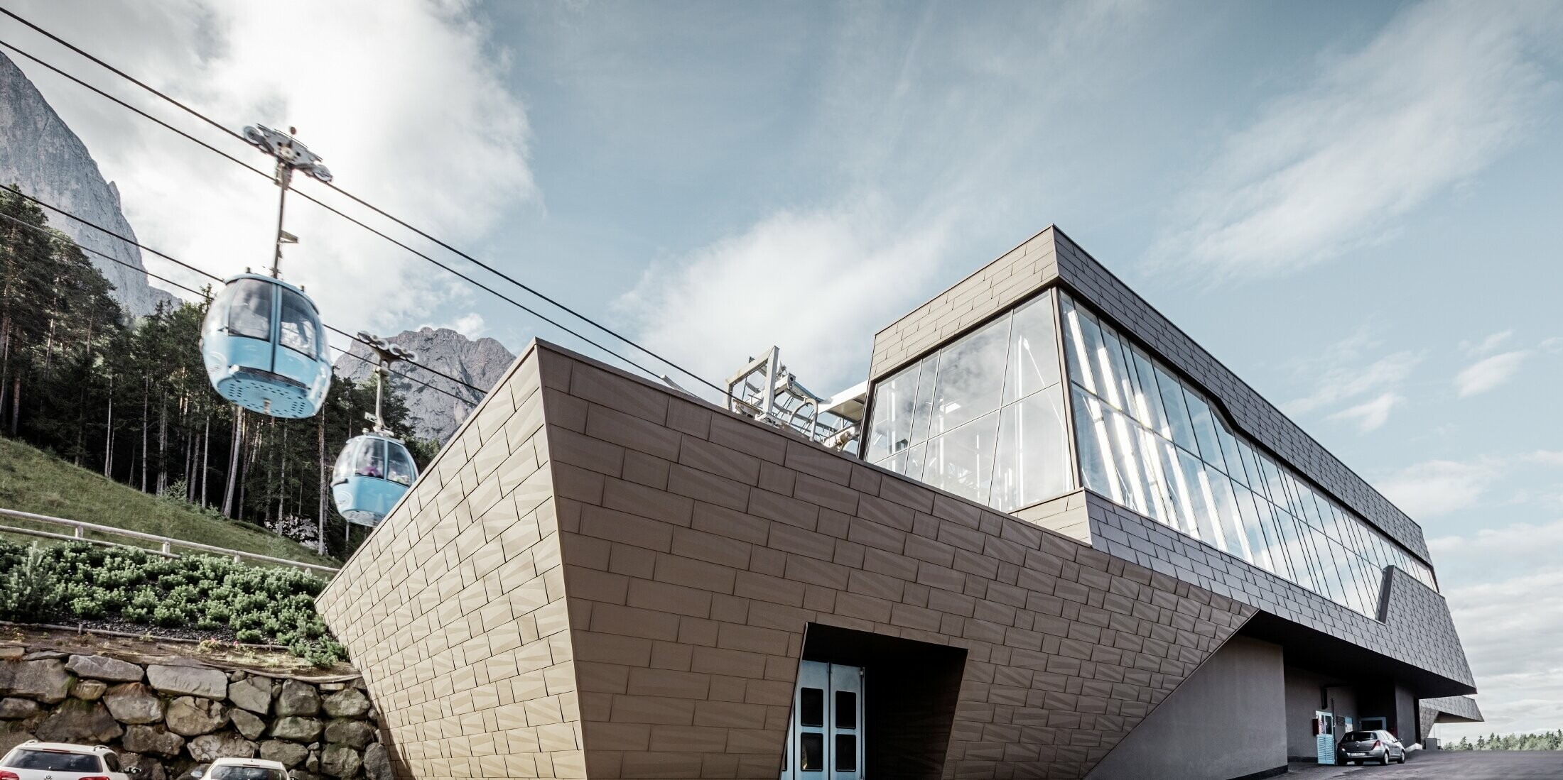 neu gestaltete Talstation der Umlaufbahn Seiser Alm, ähnlich der Dolomiten im Hintergrund mit unregelmäßigen Kanten und Oberflächen mit einer Aluminium Fassade in braun von PREFA