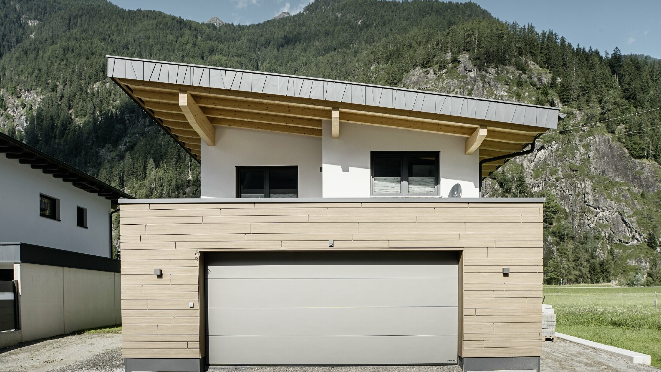 Moderner Neubau mit Pultdach und individueller Ortgangverblechung, Garage mit Flachdach und Alu-Fassade in Walnuss braun von PREFA. Die Sidings wurden horizontal verlegt und mit unterschiedlichen Baubreiten.