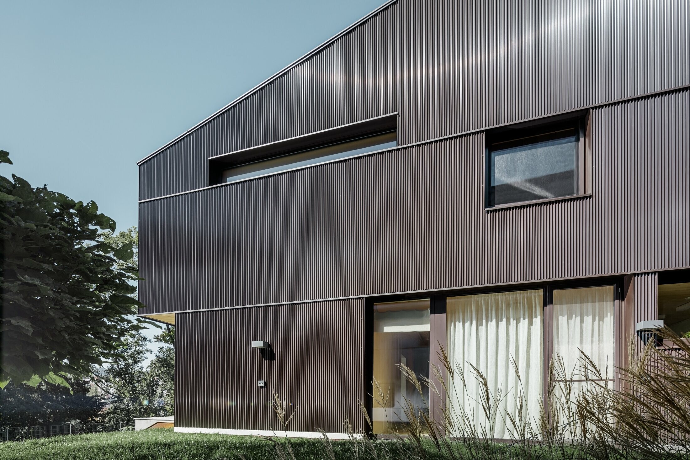 Moderna casa unifamiliare con rivestimento della facciata con profilo a zeta PREFA in marrone.