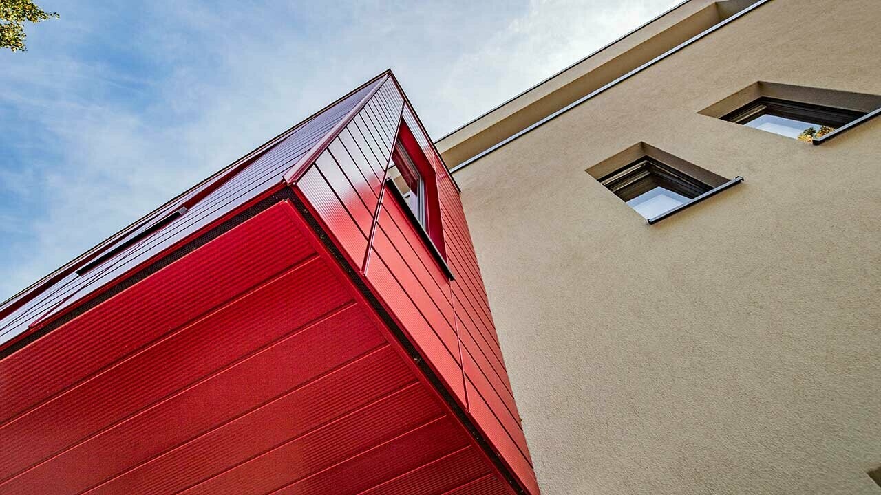 Oriel avec Sidings PREFA finition lignée couleur rouge rubis sur une maison individuelle moderne à Wernigerode, la sous-face de l’extension en porte-à-faux est photographiée ici.