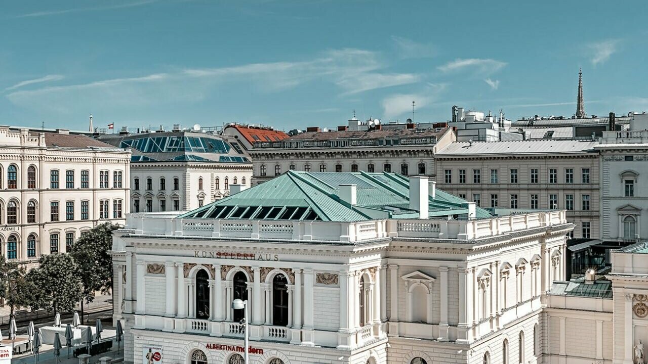 Es ist das Künstlerhaus in Wien zu sehen, umgeben von anderen Gebäuden.