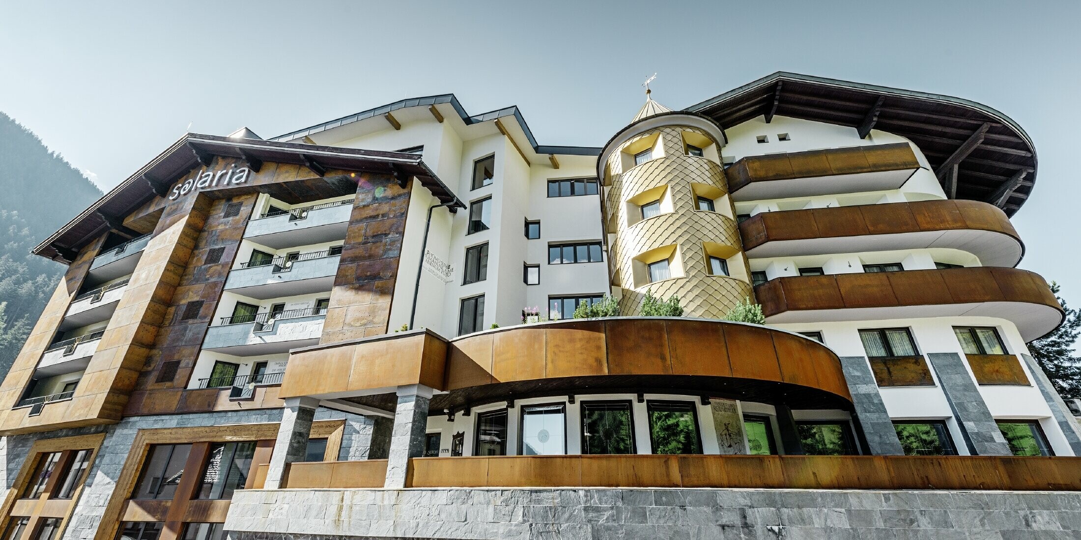 traditionelles Hotel in Ischgl mit Holzbalkonen und Holzfassade und einem Turm mit goldenen Alu-Rauten von PREFA