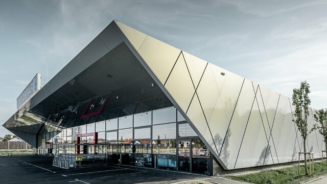 Eingangsbereich der neuen Eurospar Filiale in Wels mit der modernen Fassadenplatte von PREFA in Silver gold; Die Aluminium Verbundplatten schillern in der Sonne je nach Blickwinkel in unterschiedlichen Farben.