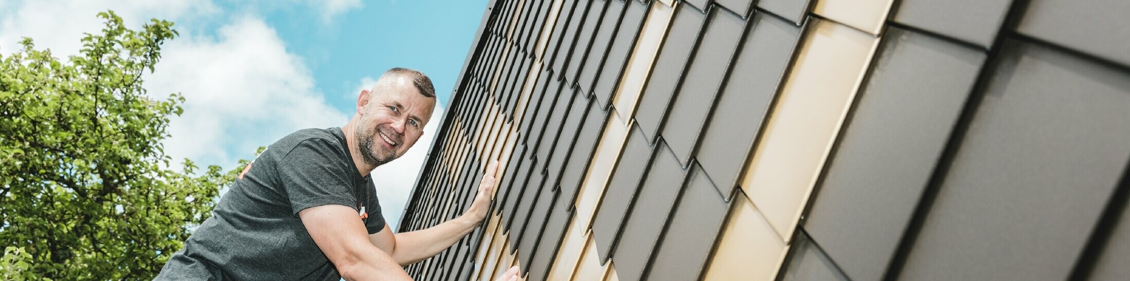 PREFA Handwerker in Ihrer Nähe an einer Fassade mit PREFA Wandrauten in Braun und Mayagold.