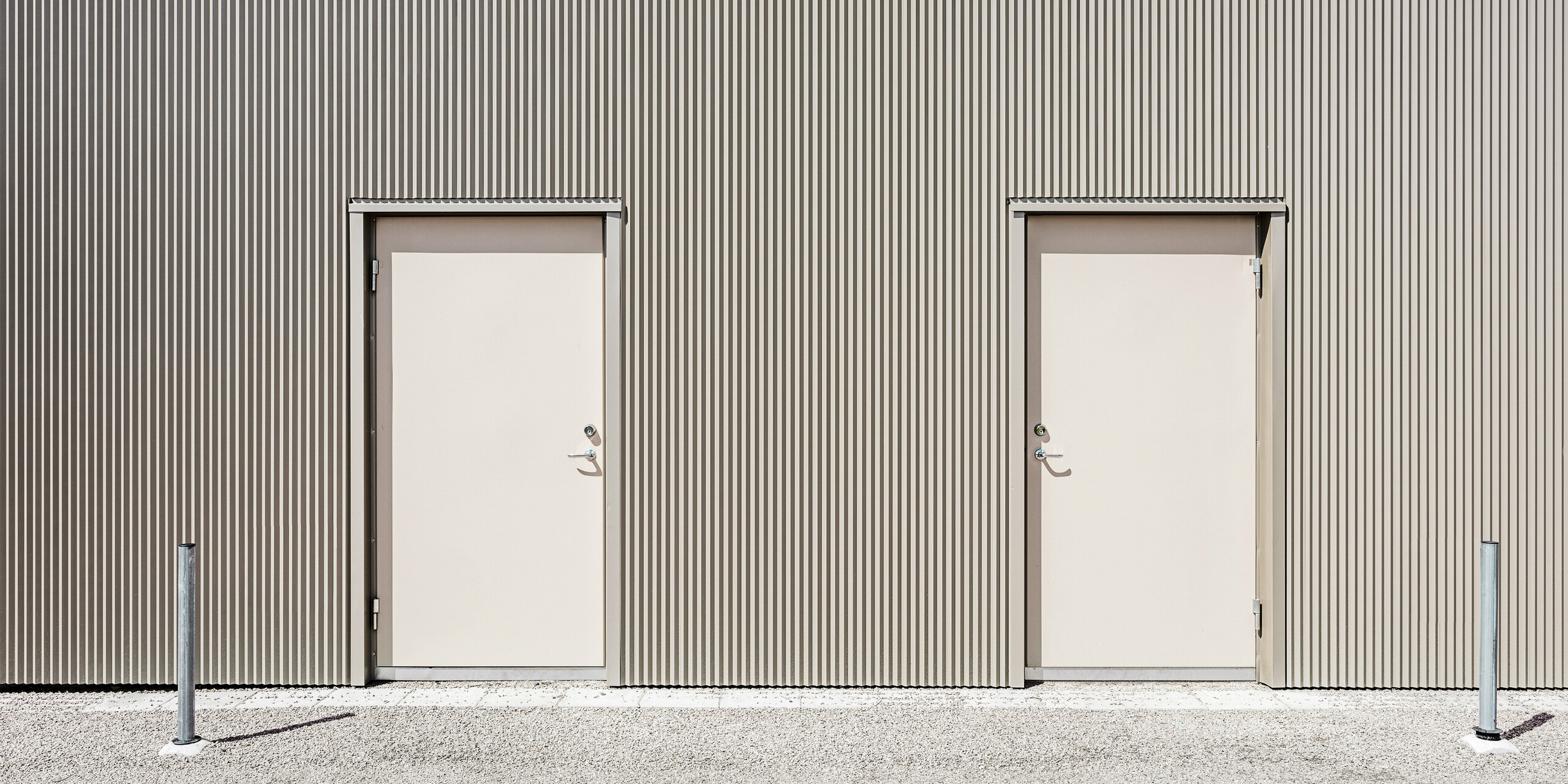 Deux portes d'entrée du Park Arena de Värnamo, en Suède. Les portes sont situées à l'arrière du bâtiment et sont en bronze, à l'image de la façade. Les portes élégamment intégrées s'intègrent harmonieusement dans la façade en aluminium. Ce design moderne et minimaliste se poursuit dans tous les espaces du Sprotzentrum et crée une image globale harmonieuse.