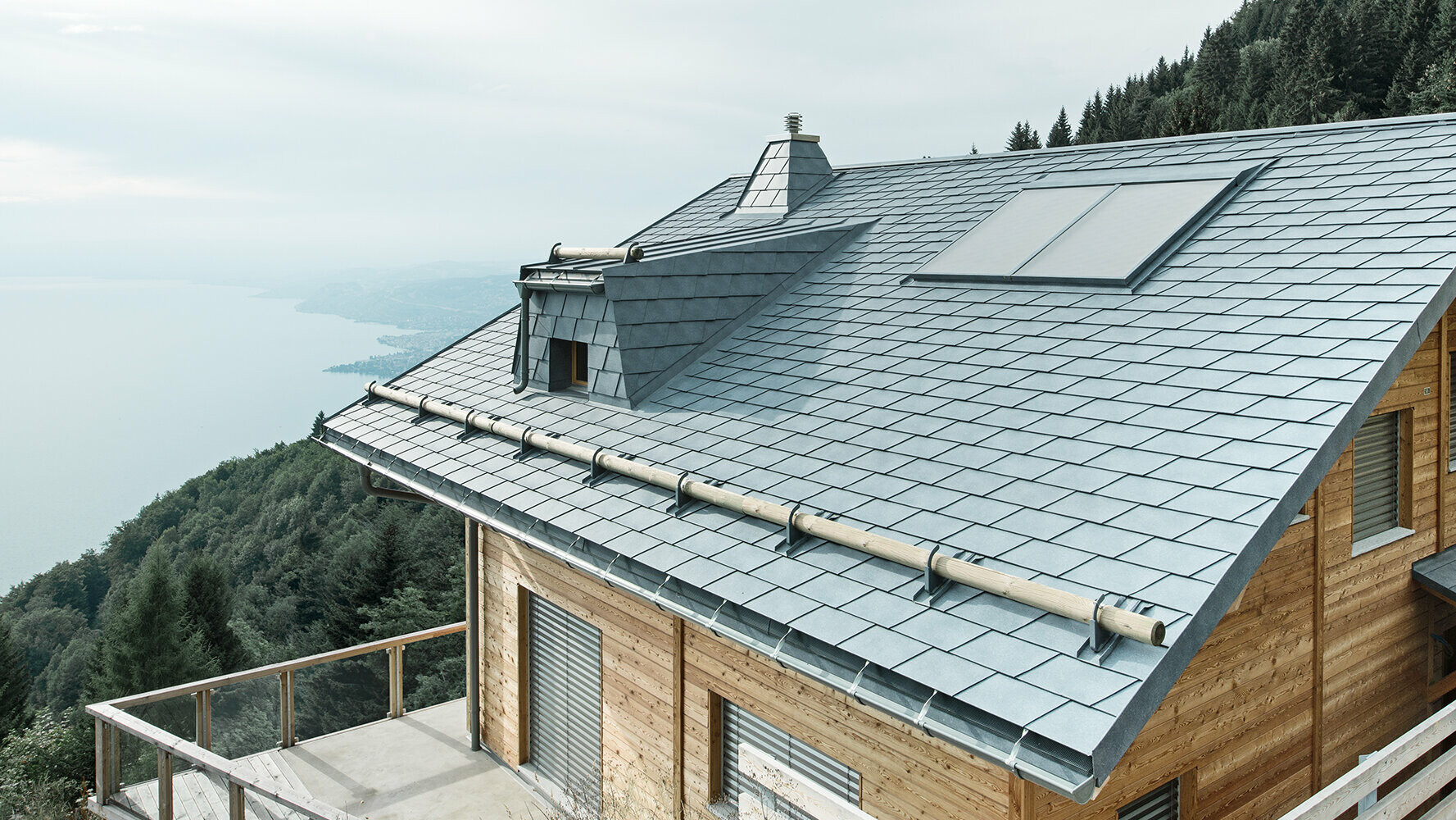 PREFA Berghütte mit Holzfassade und einem Satteldach eingedeckt mit der sturmsicheren PREFA Dachschindel in steingrau mit Gebirgsschneefang