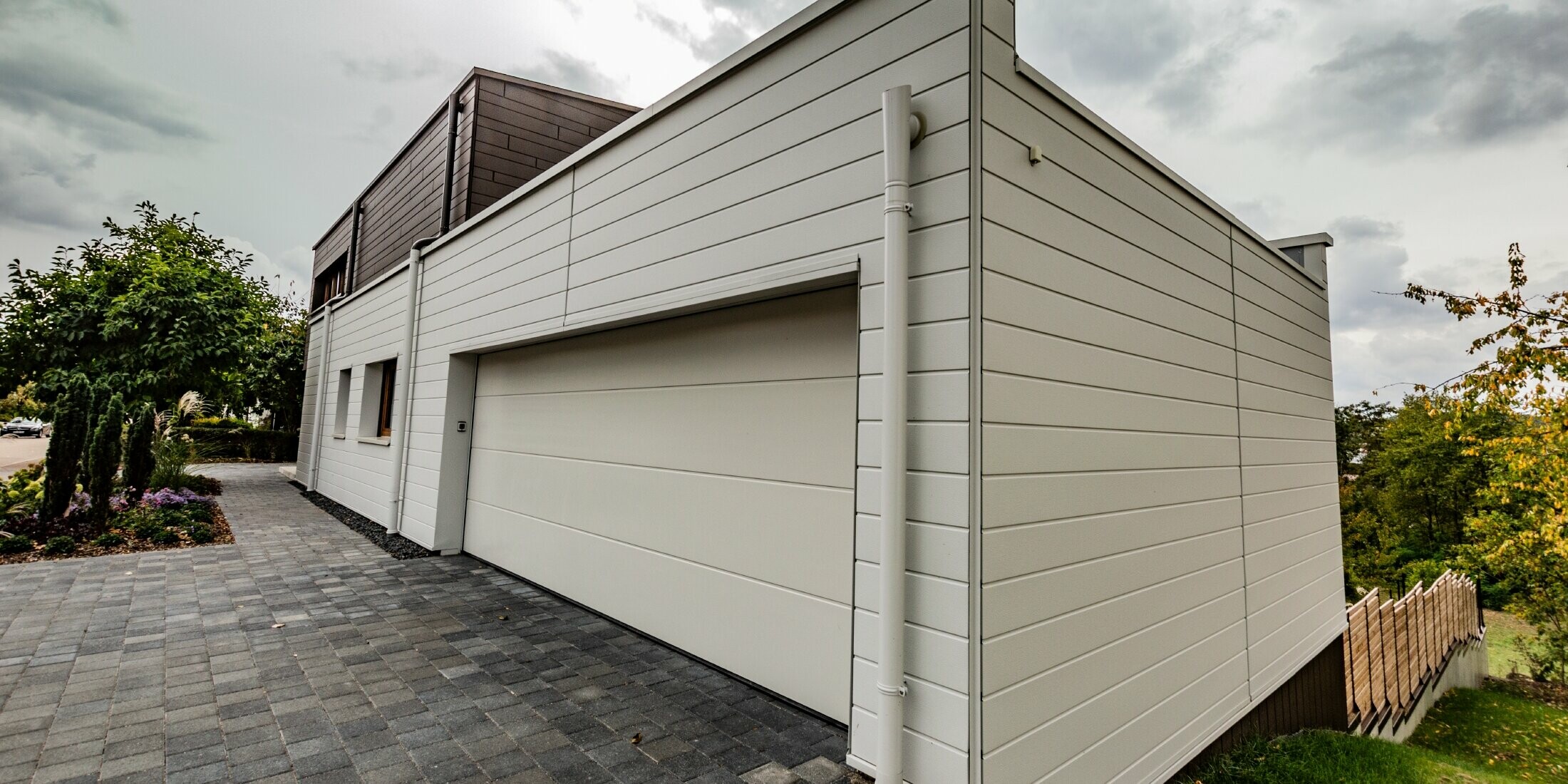 Garagenverkleidung mit den PREFA Siding in Weiß horizontal verlegt mit der PREFA Speiereinmündung.