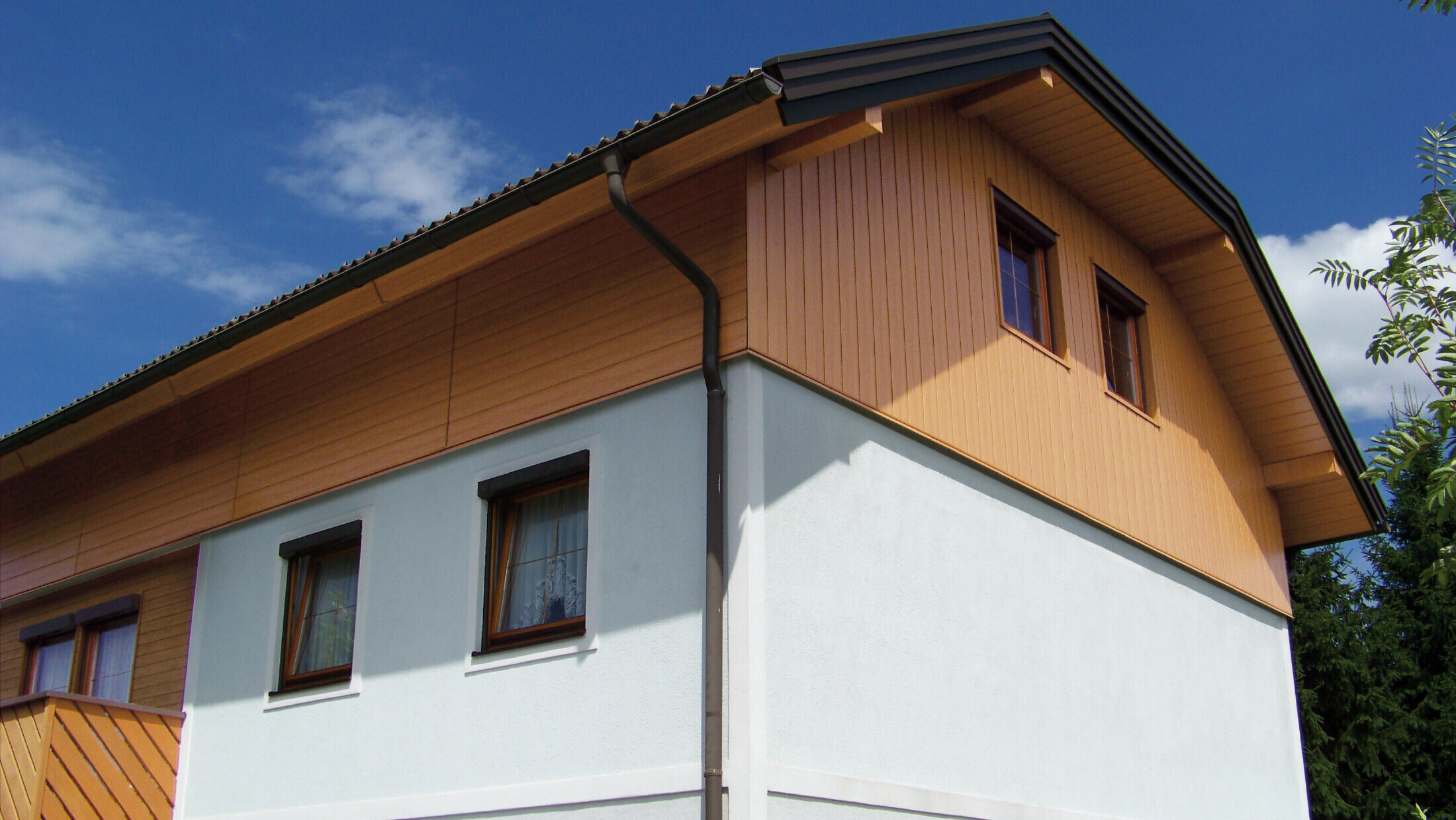 Großes Einfamilienhaus mit Krüppelwalmdach und einer Giebelverkleigung mit den PREFA Sidings in Holzoptik (Farbe Eiche natur)