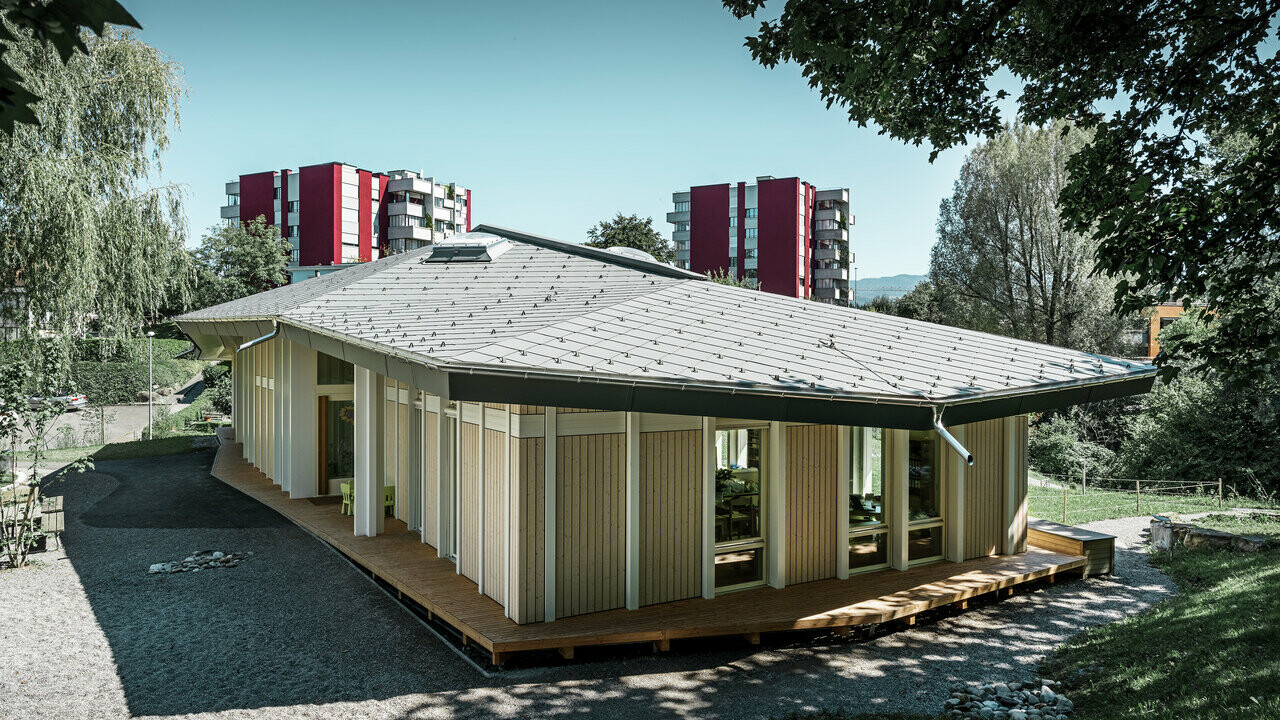 Jardin d’enfants de plain-pied avec panneaux de façade verticaux et toiture en aluminium de PREFA (losange de toiture) couleur gris souris